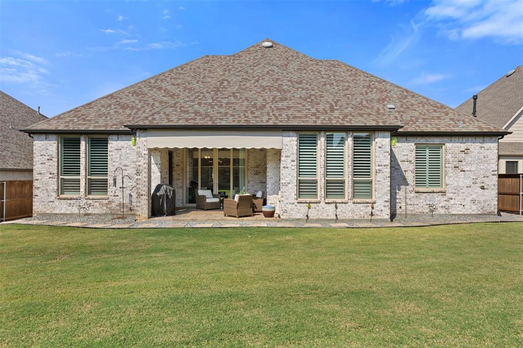 9716 Wilderness Road Little Elm, TX 75068 - Photo 35 of 39 Expansive backyard with a covered patio, featuring a retractable awning, stone paver patio, and a manicured lawn