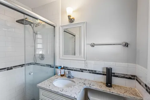 a bathroom with a granite countertop sink a mirror and shower