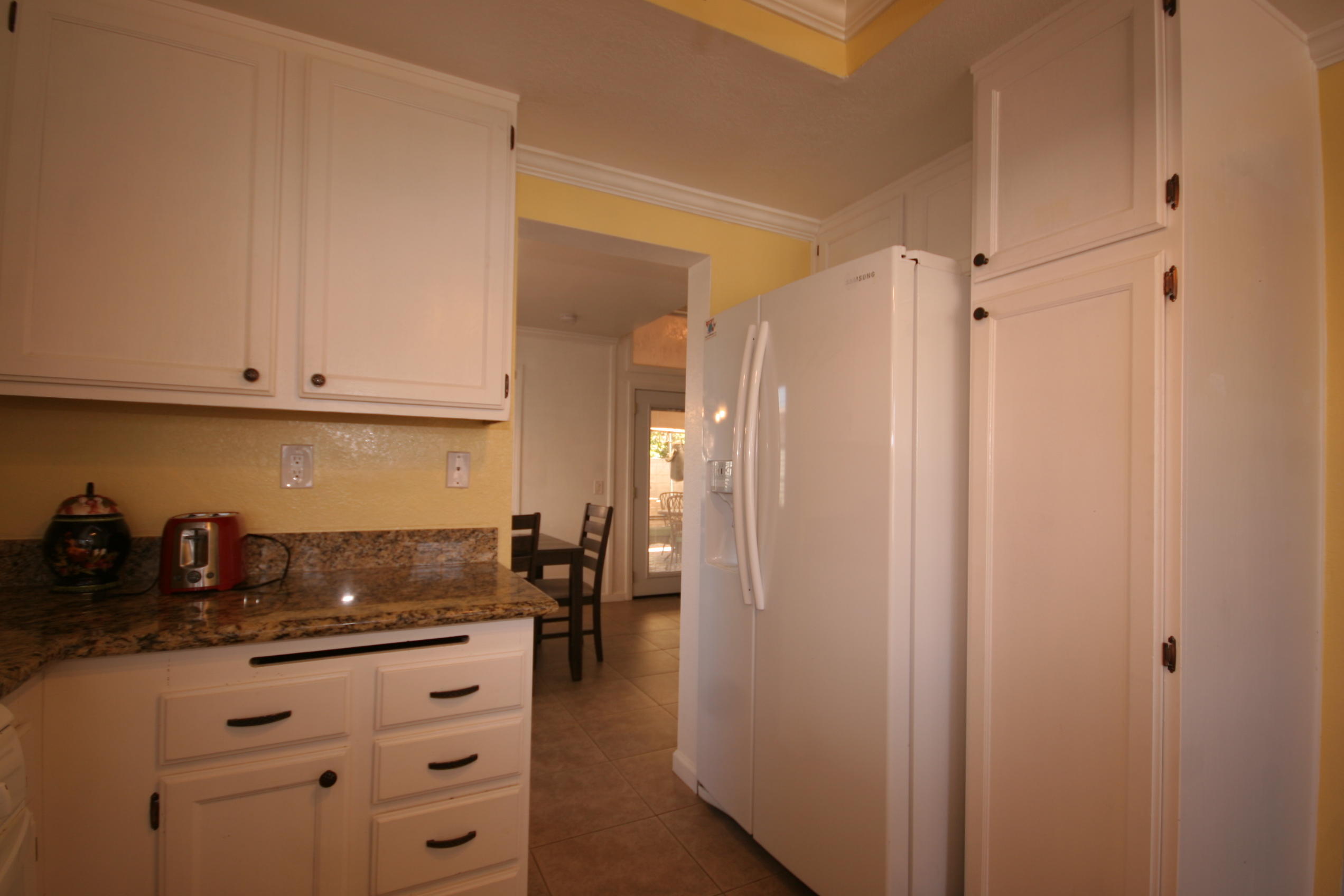 45736 Sutter Creek Road Indio, CA 92201 - Photo 18 of 44 a kitchen with granite countertop a refrigerator and white cabinets