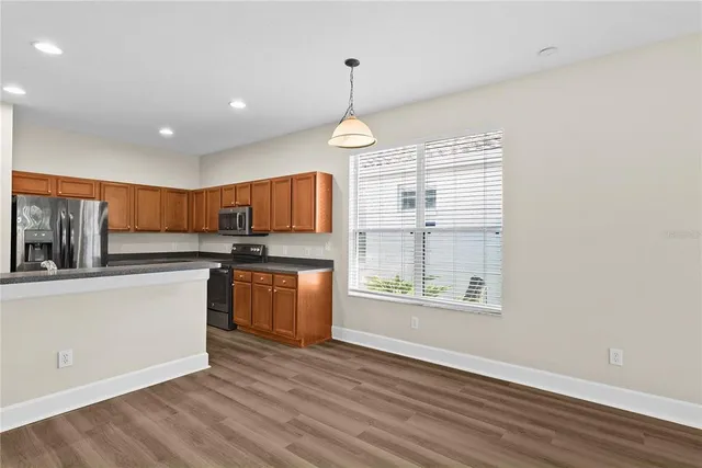 a kitchen with stainless steel appliances granite countertop a stove a sink dishwasher and a refrigerator with wooden floor