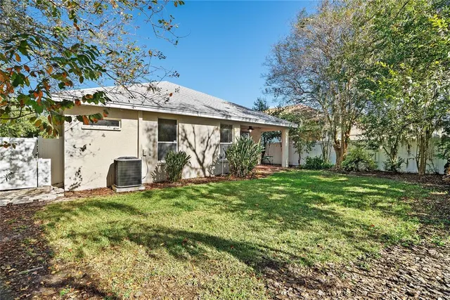 a view of a house with a yard and large tree