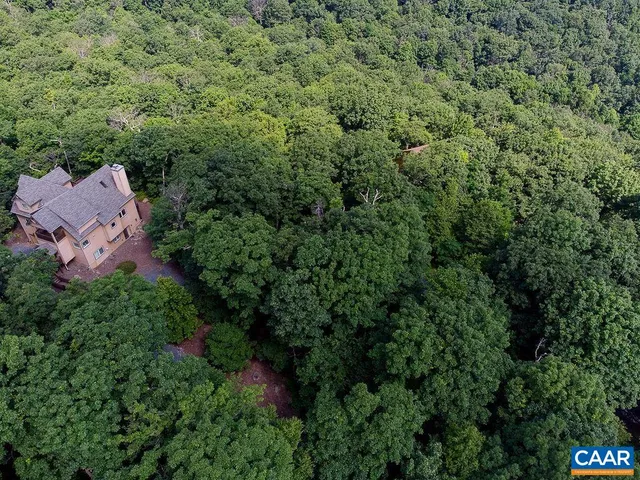 an aerial view of residential house with outdoor space and trees all around