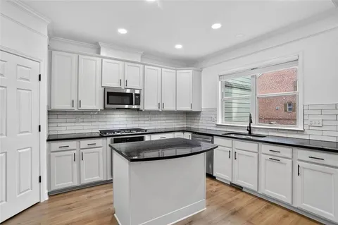 a kitchen with granite countertop white cabinets and a sink