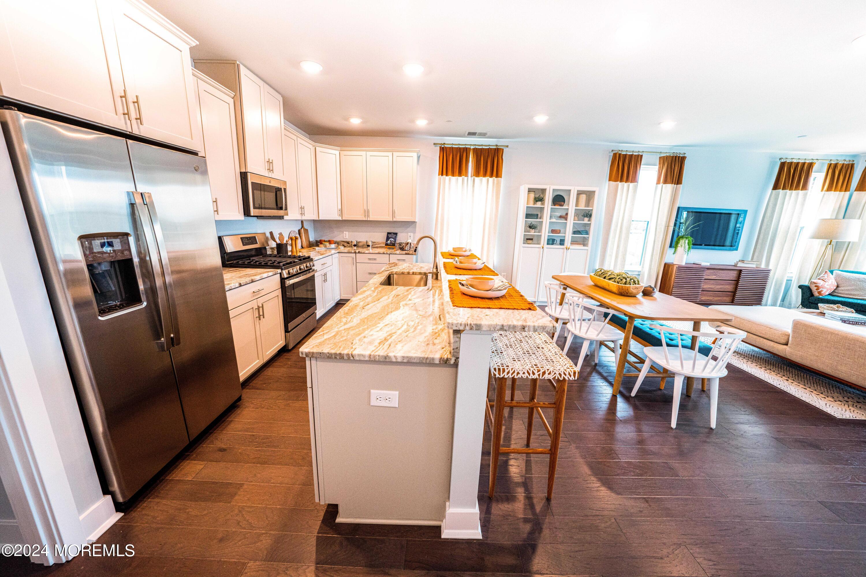 4 Midway Road South Tinton Falls, NJ 07724 - Photo 7 of 19 a kitchen with stainless steel appliances kitchen island granite countertop a refrigerator a stove a sink a dining table and chairs with wooden floor