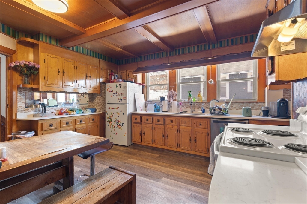 25-27 Upland Road Somerville, MA 02144 - Photo 12 of 38 a kitchen with stainless steel appliances granite countertop a stove a refrigerator a sink and white cabinets
