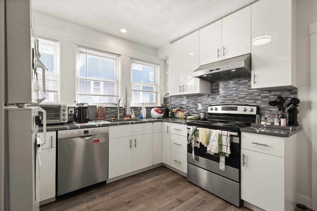 25-27 Upland Road Somerville, MA 02144 - Photo 20 of 38 a kitchen with stainless steel appliances granite countertop a stove a sink and white cabinets