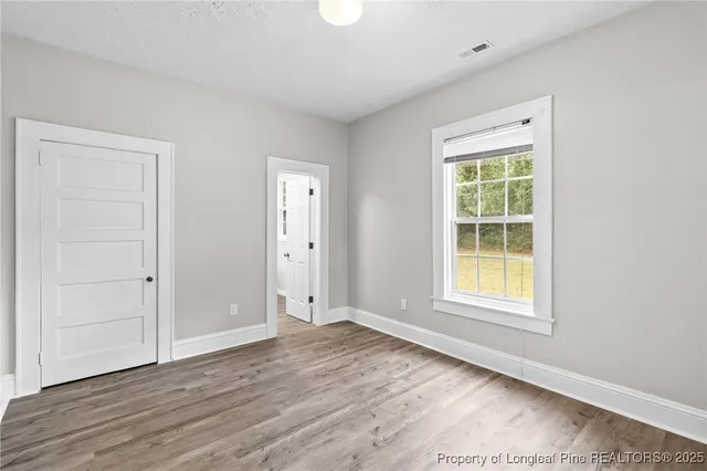 an empty room with wooden floor and window