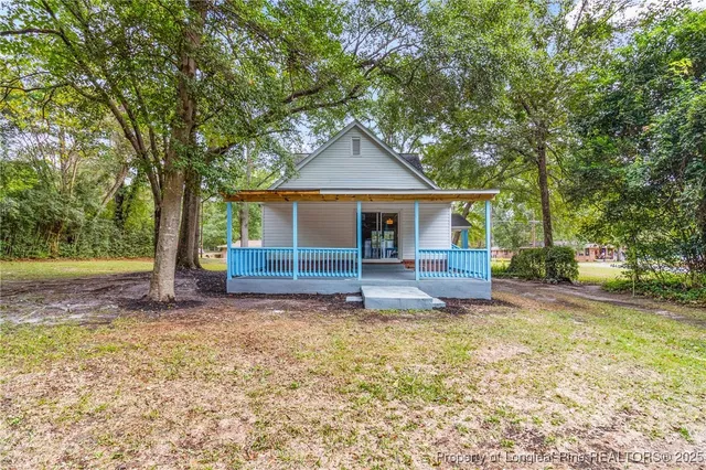 a view of a house with a yard and large tree