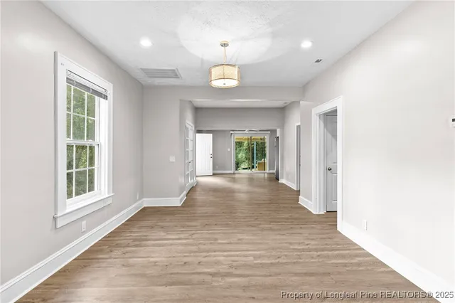 a view of an empty room with a window and wooden floor