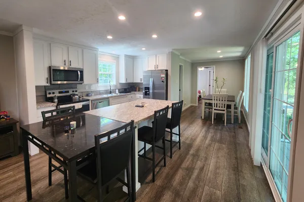 a kitchen with stainless steel appliances granite countertop a dining table chairs stove refrigerator and cabinets