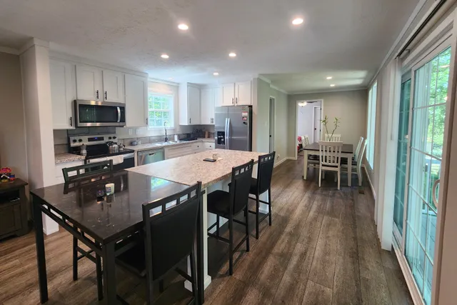 a kitchen with stainless steel appliances granite countertop a dining table chairs stove refrigerator and cabinets