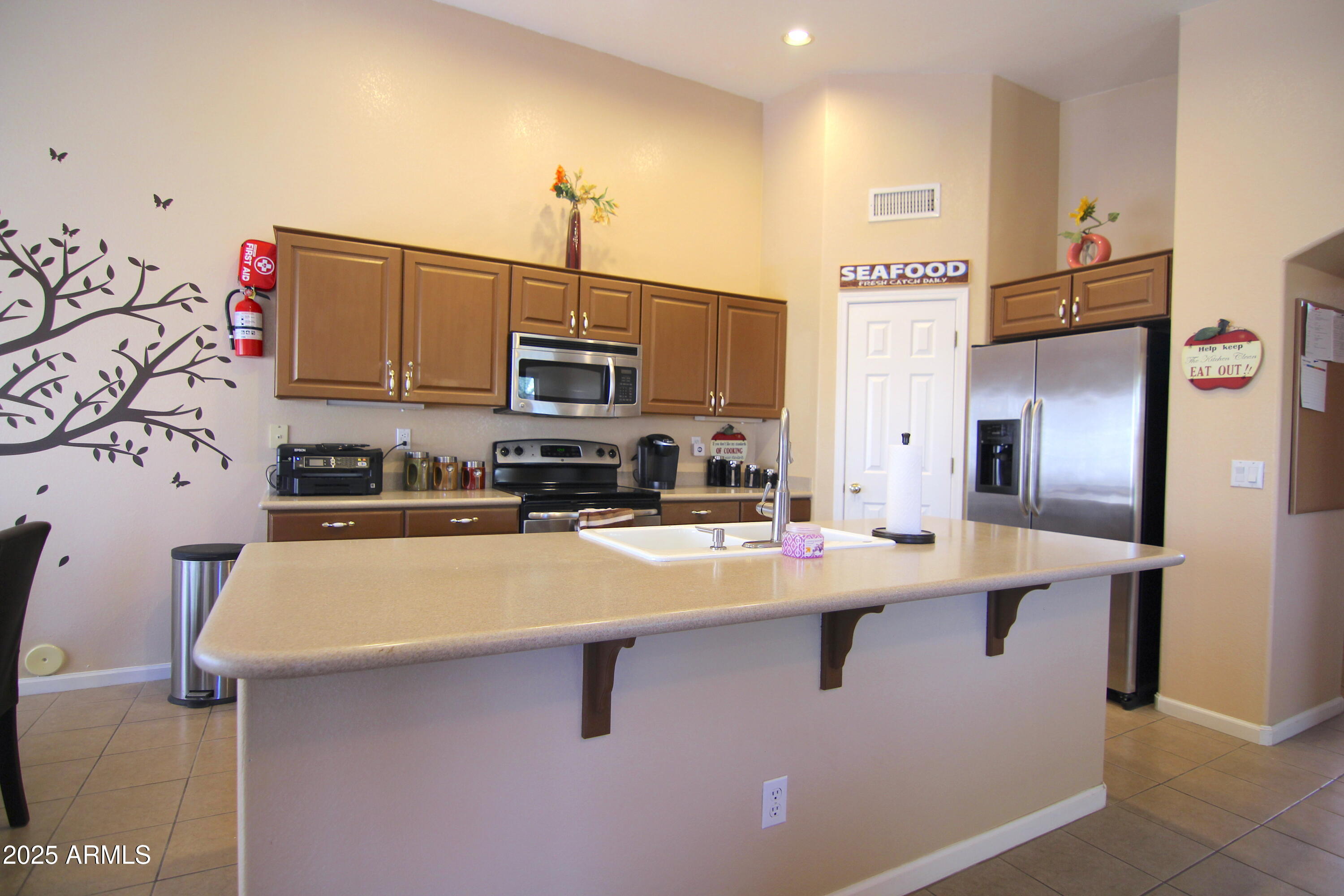3569 East Utopia Road Phoenix, AZ 85050 - Photo 11 of 16 a kitchen with stainless steel appliances a sink a stove a refrigerator a center island and cabinets