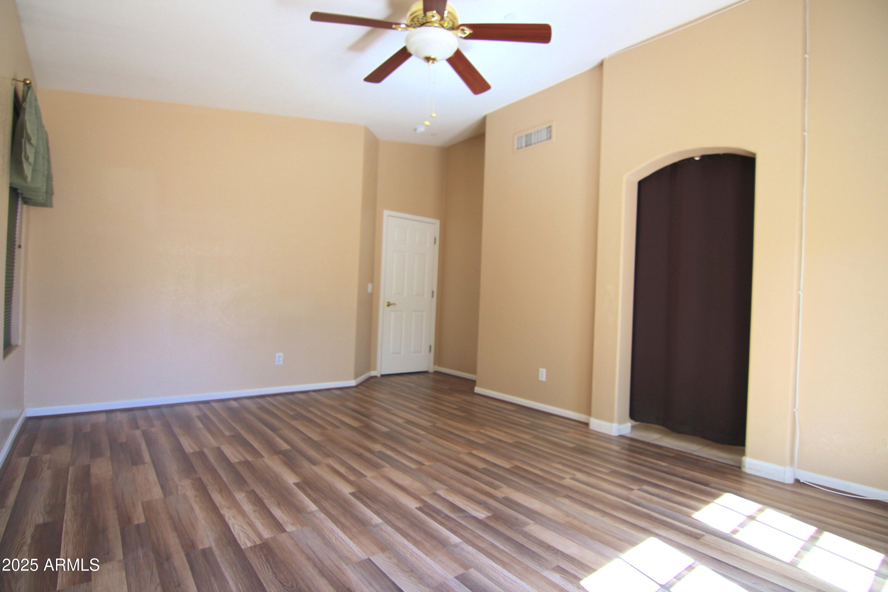 3569 East Utopia Road Phoenix, AZ 85050 - Photo 4 of 16 a view of an empty room with wooden floor and a ceiling fan
