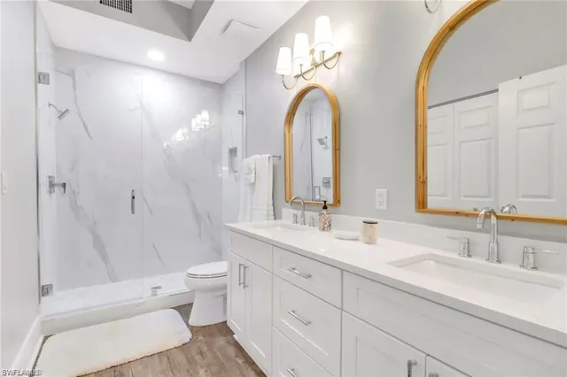 a spacious bathroom with a double vanity sink a toilet and a mirror