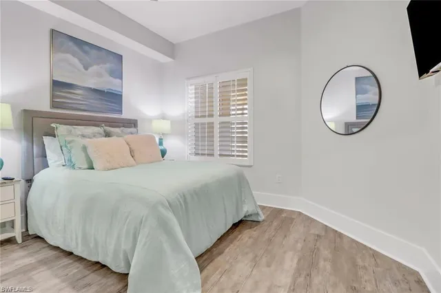 a bedroom with a bed and a large mirror next to window