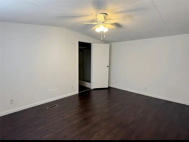 an empty room with wooden floor and chandelier fan
