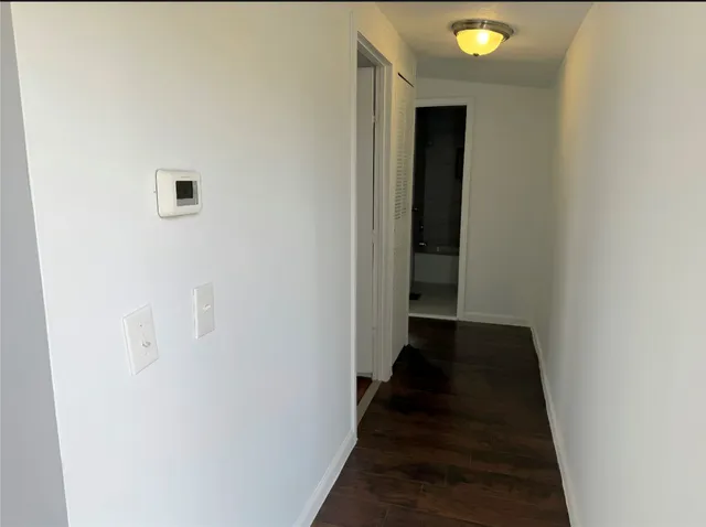 a view of a hallway with wooden floor and a bathroom