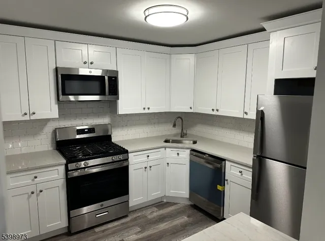 a kitchen with stainless steel appliances a refrigerator stove and white cabinets