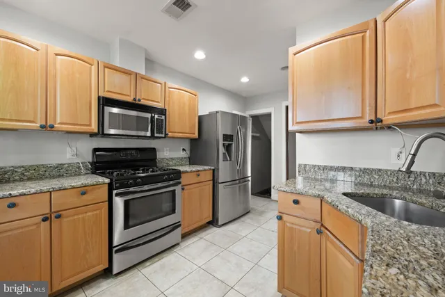 a kitchen with stainless steel appliances granite countertop a stove a sink and a microwave