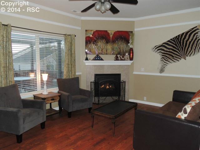 6797 Akron Road Colorado Springs, CO 80923 - Photo 12 of 23 Crisp and Warm Family Room with Gas Fireplace... the perfect place to catch up with family after a busy day! Tremendous details in moldings, decorator touches, ceiling fan and gorgeous flooring!