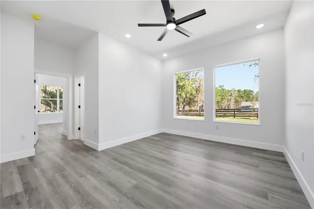 an empty room with windows and chandelier fan
