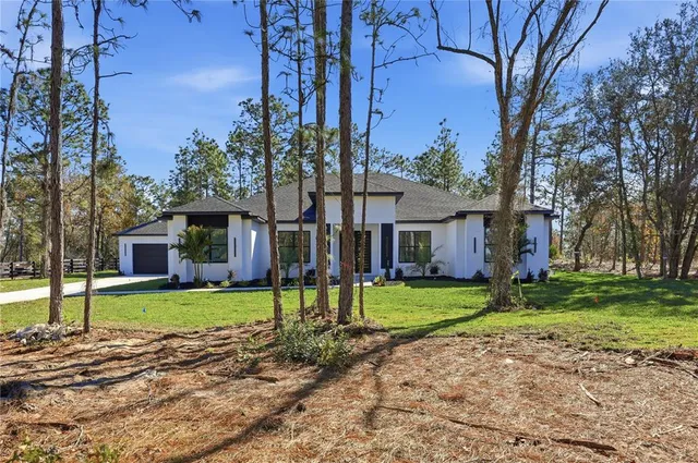 a front view of a house with a garden and trees