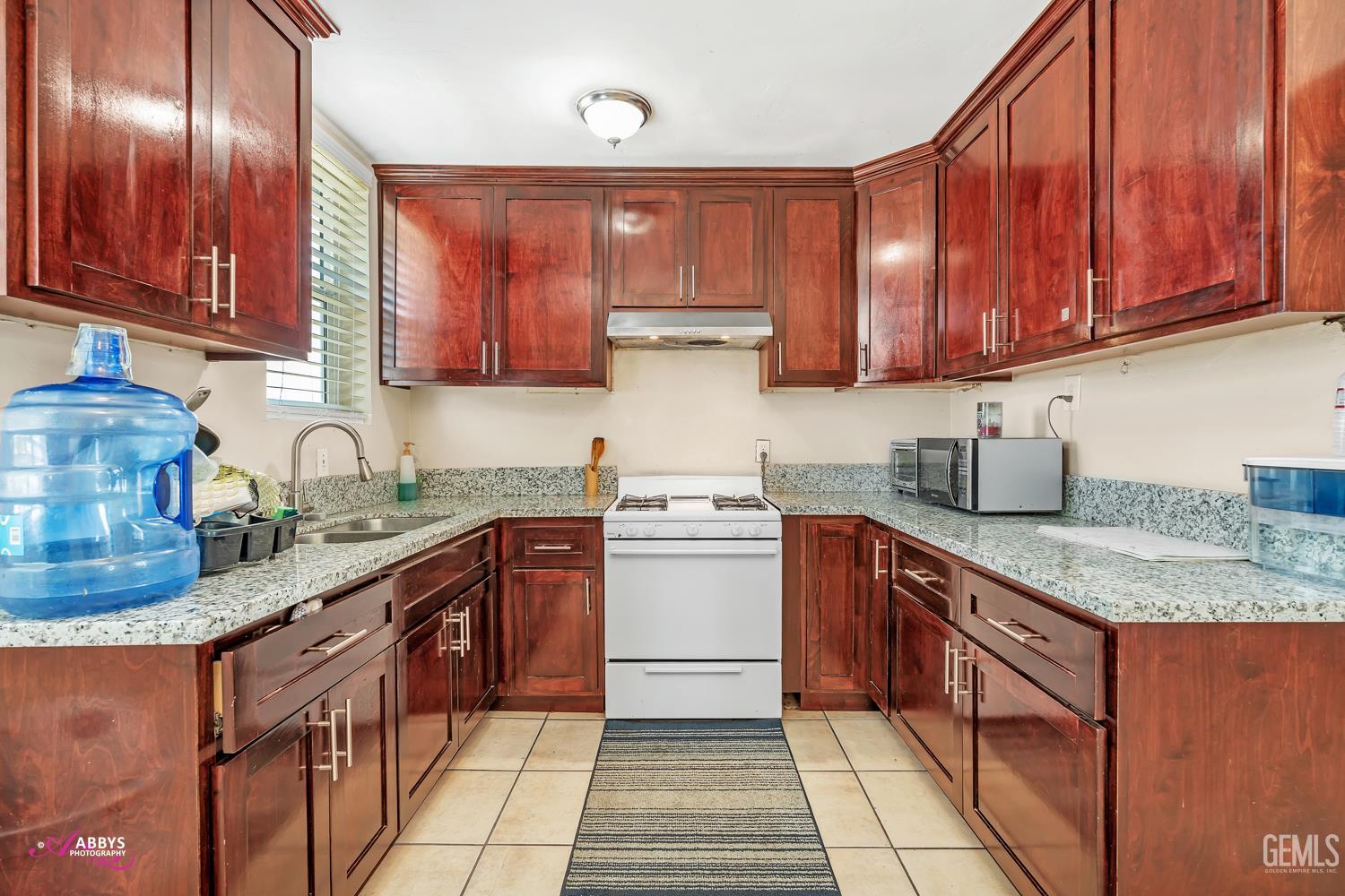 Undisclosed Address Bakersfield, CA 93307 - Photo 47 of 62 a kitchen with stainless steel appliances granite countertop wooden cabinets a stove top oven a sink and dishwasher
