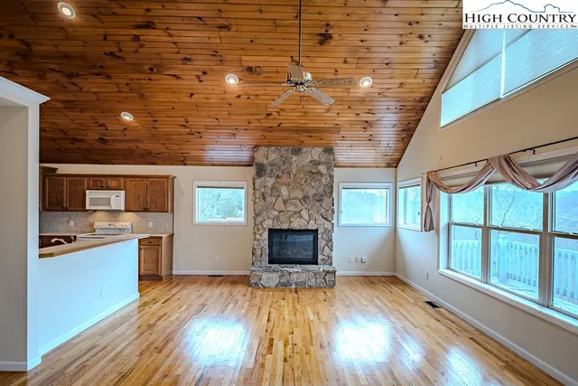 a living room with stainless steel appliances wooden floors and fireplace