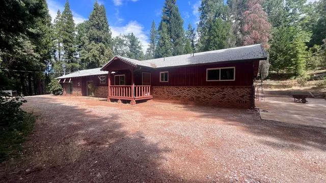 a backyard of a house with table and chairs under an large tree