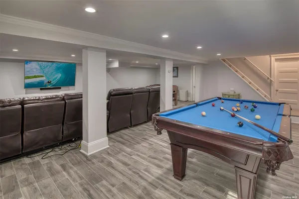 a room with furniture pool table wooden floor and kitchen view