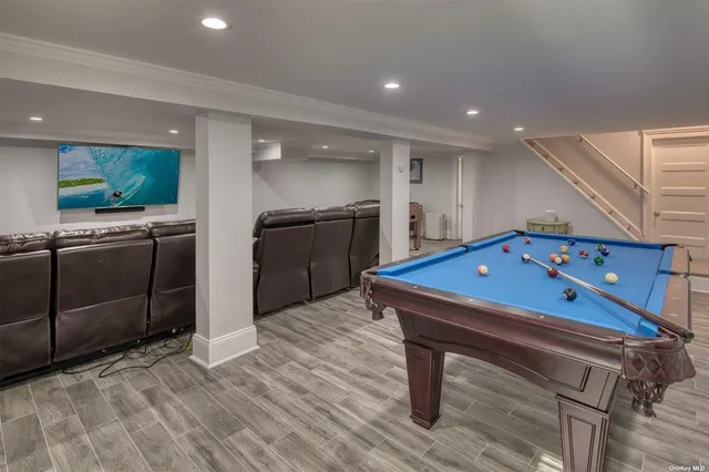a room with furniture pool table wooden floor and kitchen view