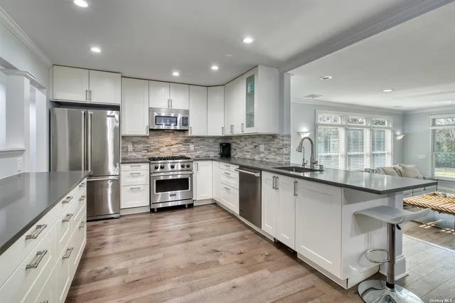 a large kitchen with stainless steel appliances granite countertop a stove refrigerator and a sink