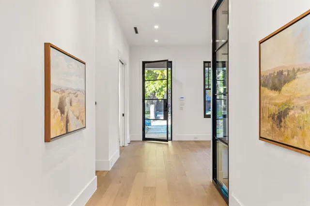 a view of hallway with wooden floor and wall paintings