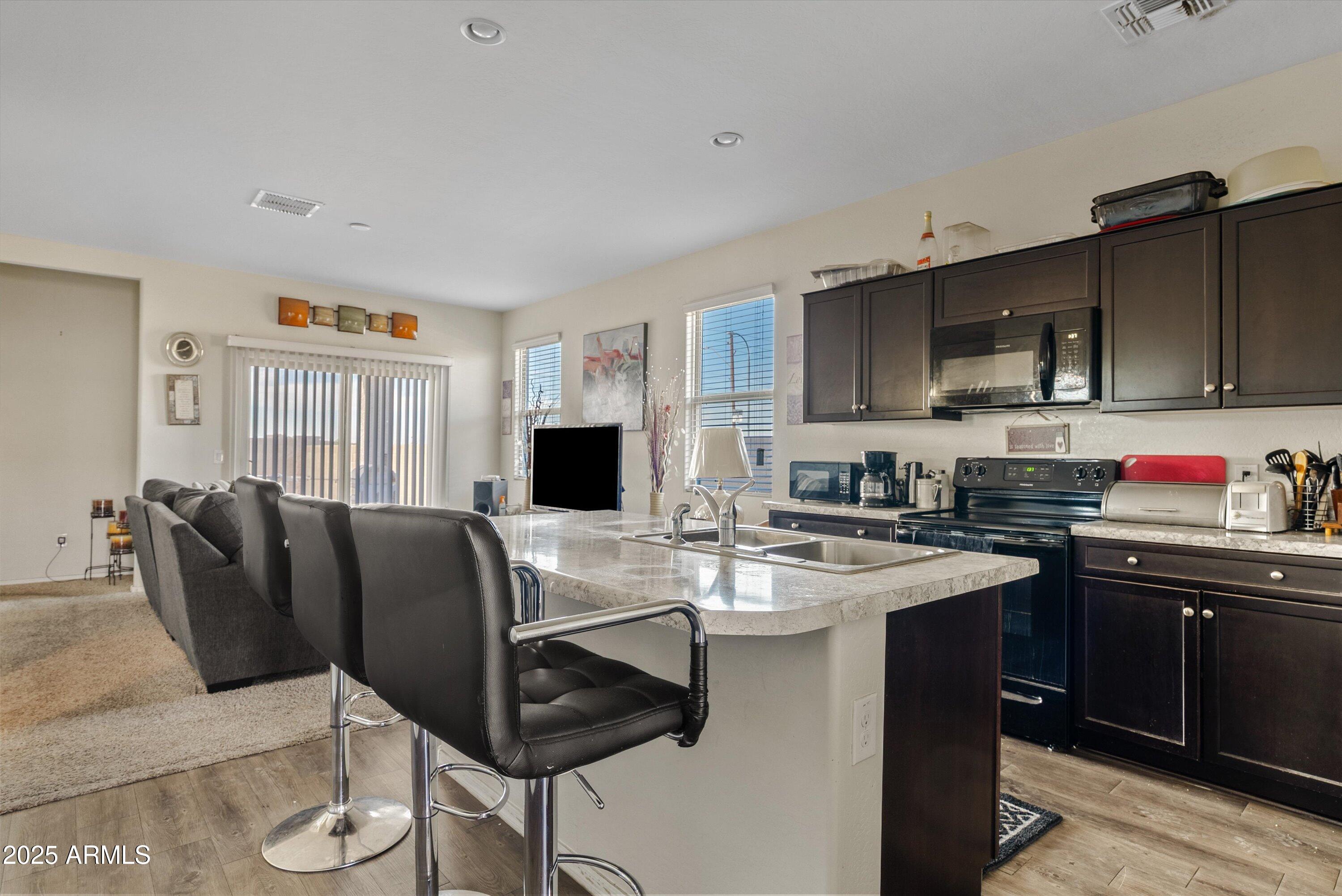 4708 South 26th Lane Phoenix, AZ 85041 - Photo 7 of 23 a open kitchen with stainless steel appliances granite countertop a stove top oven a sink dishwasher and white cabinets with wooden floor