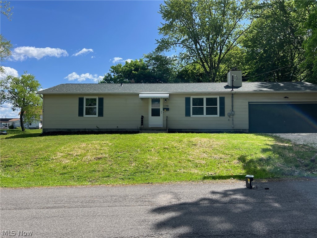 Single story home featuring a garage and a front yard