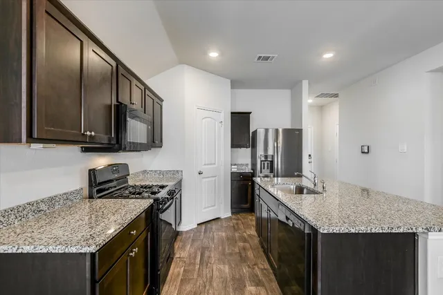 a kitchen with stainless steel appliances granite countertop a kitchen island a stove a refrigerator and a sink