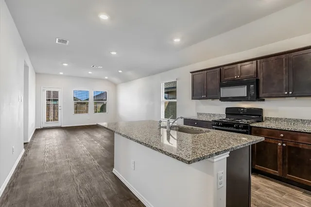 a kitchen with stainless steel appliances granite countertop a stove a sink and a microwave