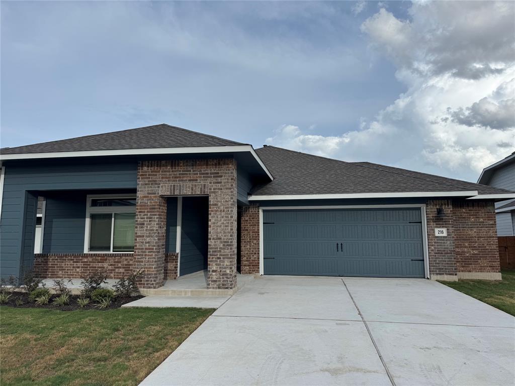 Contemporary single-story residence featuring a brick and siding exterior, an attached two-car garage with a dark teal door, and a concrete driveway