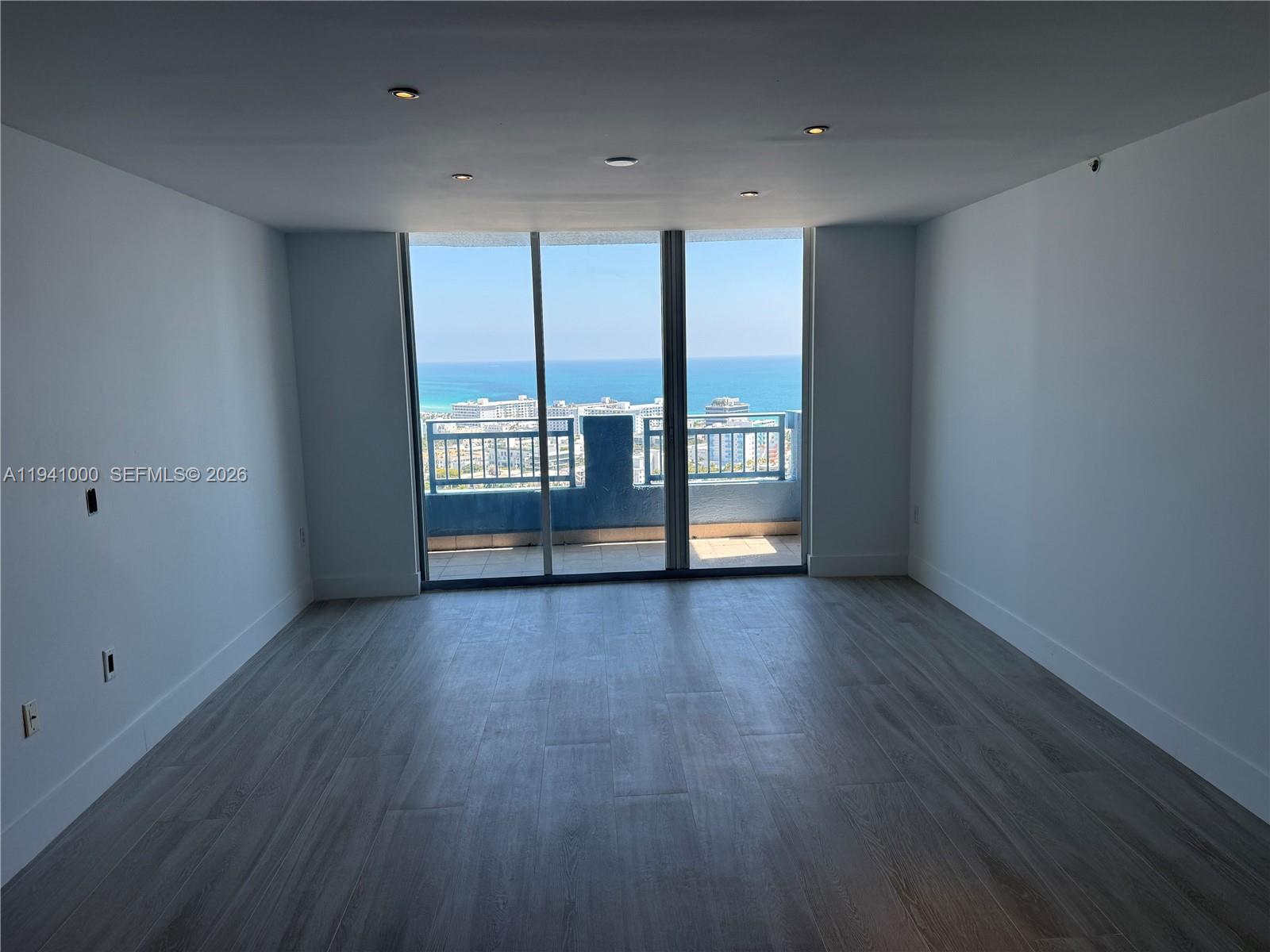 90 Alton Road, Unit 2803 Miami Beach, FL 33139 - Photo 3 of 21 an empty room with wooden floor and windows