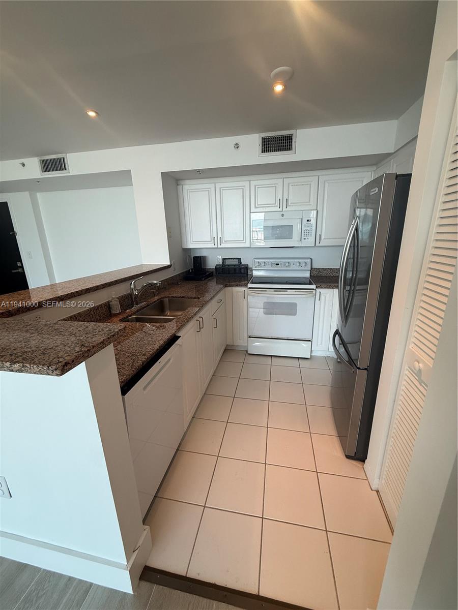 90 Alton Road, Unit 2803 Miami Beach, FL 33139 - Photo 4 of 21 a kitchen with a sink a stove top oven and cabinetry
