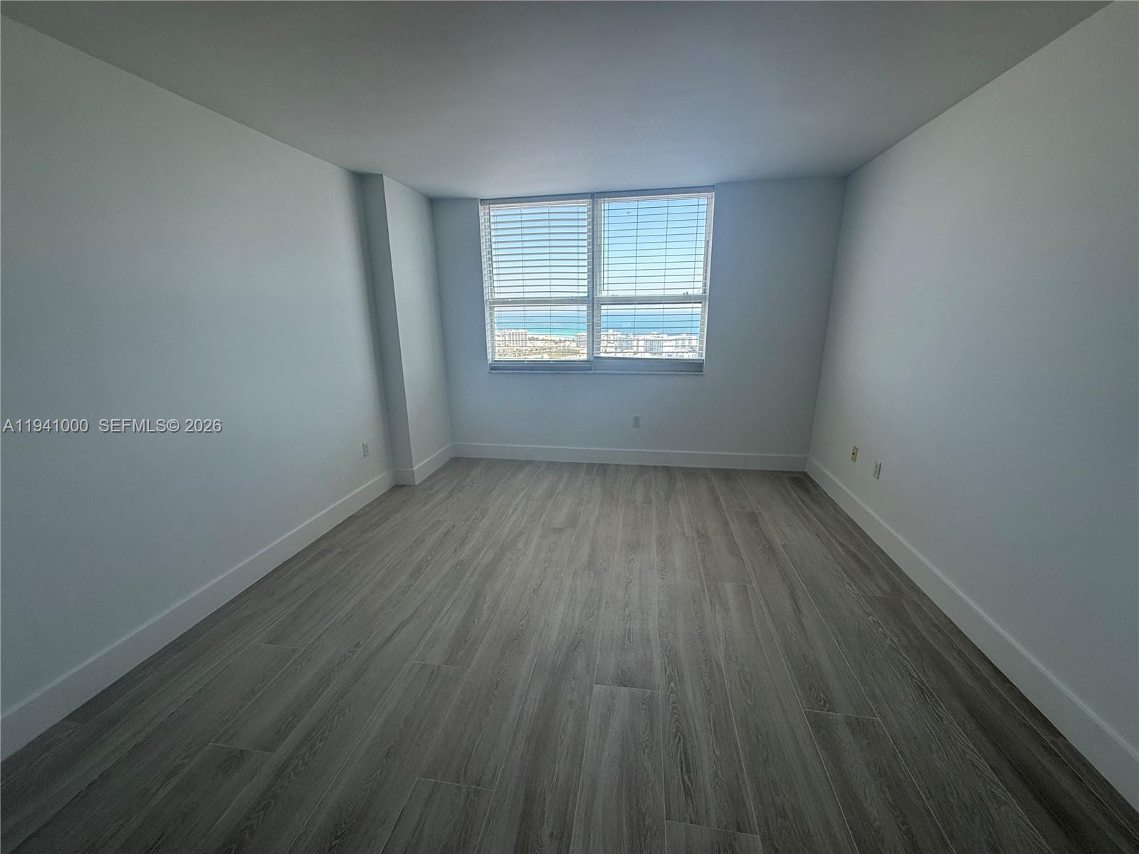 90 Alton Road, Unit 2803 Miami Beach, FL 33139 - Photo 7 of 21 an empty room with wooden floor and windows
