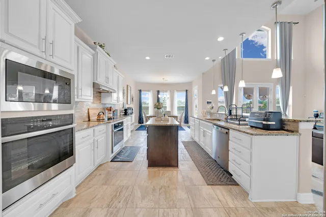 a large kitchen with stainless steel appliances kitchen island granite countertop a large counter top and a stove