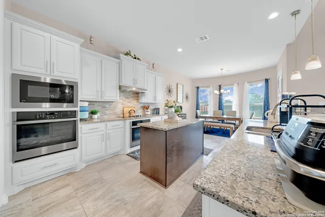 a kitchen with stainless steel appliances kitchen island granite countertop a stove a sink and a microwave