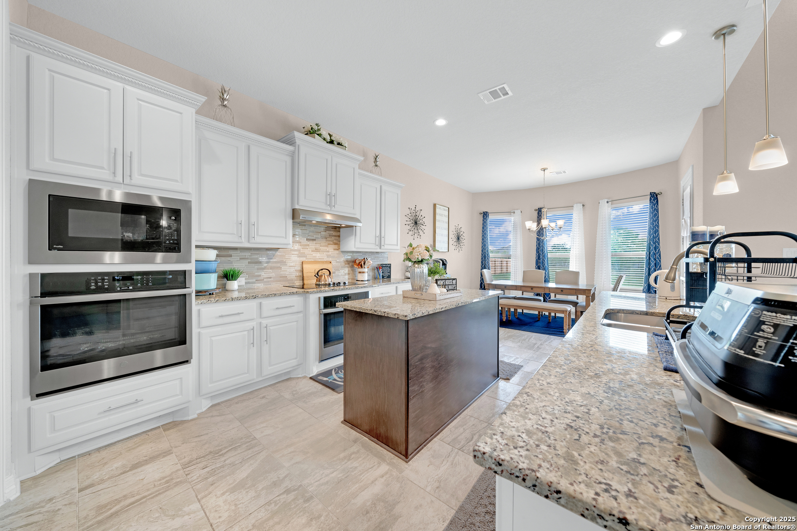 7151 Agarita Mist Fair Oaks Ranch, TX 78015 - Photo 13 of 49 a kitchen with stainless steel appliances kitchen island granite countertop a stove a sink and a microwave
