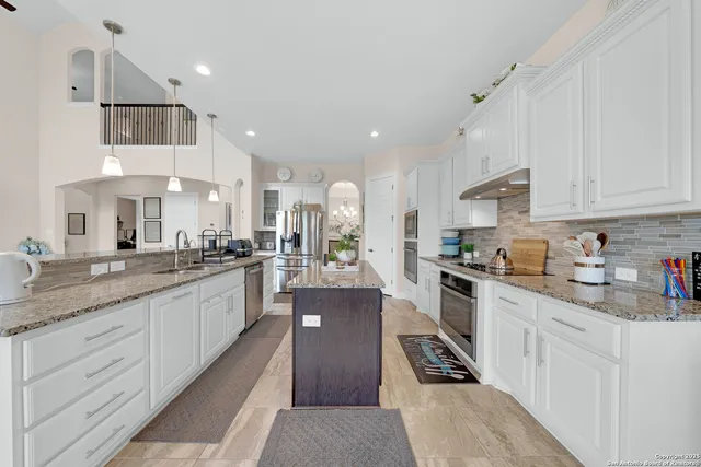 a kitchen with stainless steel appliances granite countertop a stove oven and white cabinets