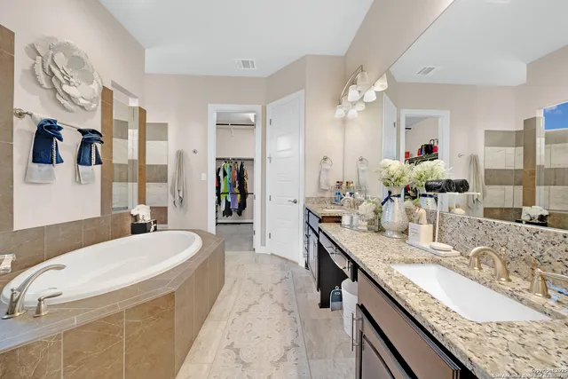 a bathroom with a granite countertop sink a large mirror and a bathtub