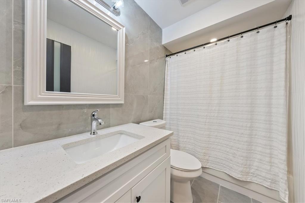 5841 Rattlesnake Hammock Road, Unit 2 Naples, FL 34113 - Photo 13 of 21 a bathroom with a sink a toilet and shower curtain