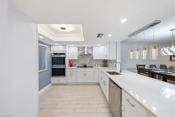 a large white kitchen with cabinets a sink and appliances
