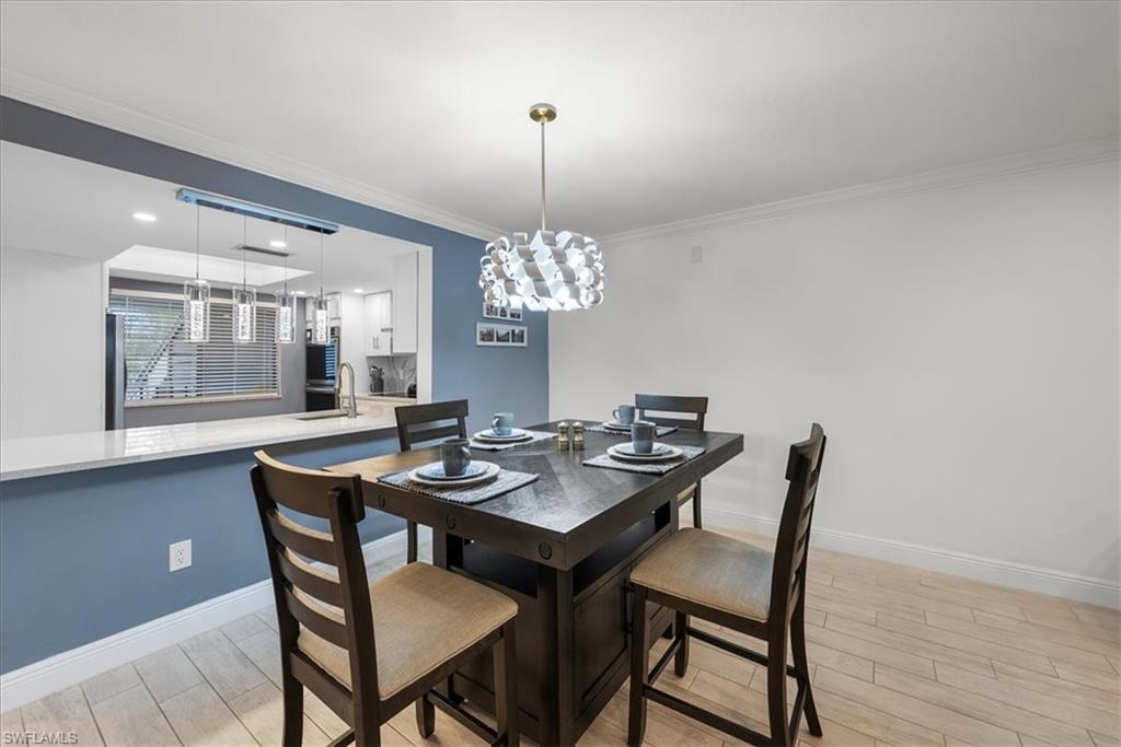 5841 Rattlesnake Hammock Road, Unit 2 Naples, FL 34113 - Photo 10 of 21 a dining room with furniture a chandelier and wooden floor