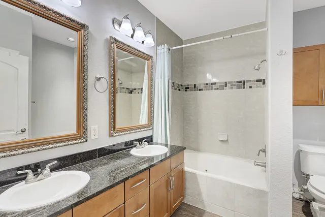 a bathroom with a granite countertop tub sink double vanity and mirror